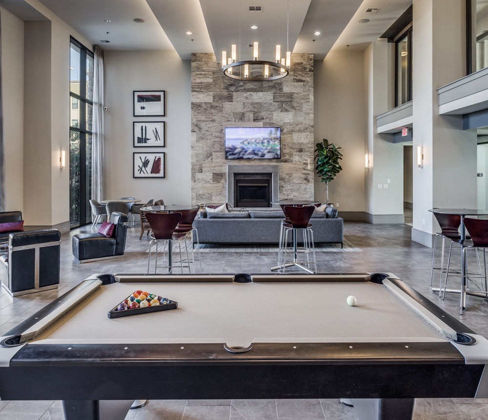 billiards table in luxurious clubhouse with chandelier, high ceilings and fireplace